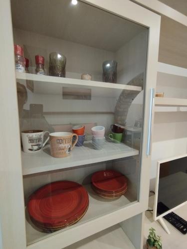 un armadio pieno di piatti e tazze rossi di La casetta di Patry a Tarquinia