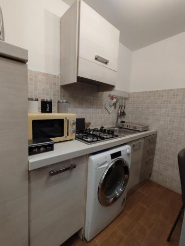 uma cozinha com uma máquina de lavar roupa e um micro-ondas em La casetta di Patry em Tarquinia
