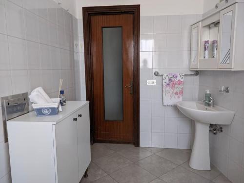 Un baño con lavabo, inodoro y puerta. en Casa Vacanze Farinella, en Putignano
