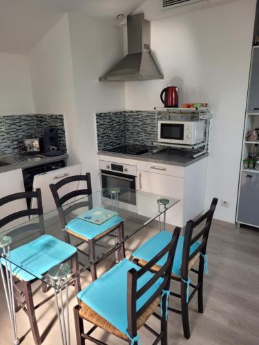 une cuisine avec une table en verre et quatre chaises dans l'établissement Appartements Au Cros De Cagnes, à Cros-de-Cagnes