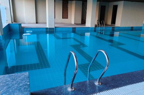 a swimming pool with blue water in a building at The Ten - Cozy 2bhk in Baner in Pune