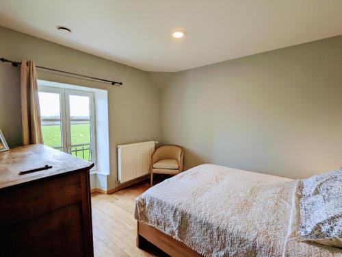 a bedroom with a bed with a dresser and a window at Gîte familial rénové avec piscine, jardin de 1 hectare et vélos à disposition, situé en pleine campagne - FR-1-591-579 in Tilly