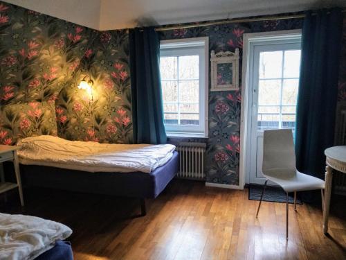 ein Schlafzimmer mit einem Bett und zwei Fenstern in der Unterkunft Villa Signedal Hostel in Kvidinge