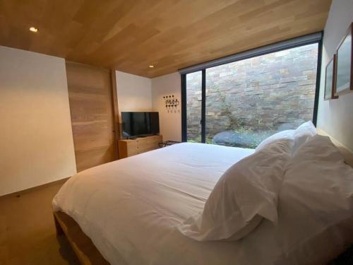 una camera da letto con un letto grande e una grande finestra di Desnivel a Valle de Bravo