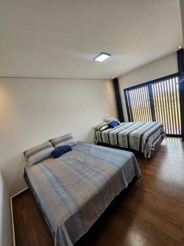 a bedroom with two beds and a window at Casa de Alto Padrão na Represa de Avaré in Paranapanema