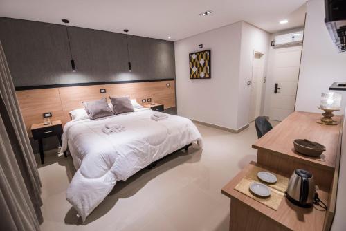 Un dormitorio con una gran cama blanca y un escritorio. en Hotel Bel Posto by Tandem, en Realicó