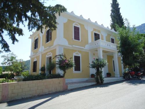 a yellow and white house with a motorcycle parked in front at Nymph in Sálakos