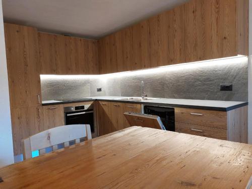 a kitchen with a wooden table and a wooden table and chairs at LA POESIA DOLOMITI APARTMENTS in Rivamonte
