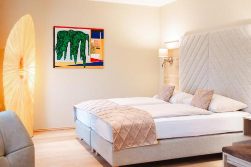 a bedroom with a white bed and a painting on the wall at Hotel Krone in Mondsee
