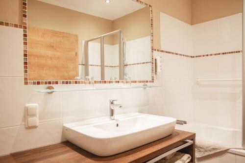 a white bathroom with a sink and a mirror at Hotel Krone in Mondsee