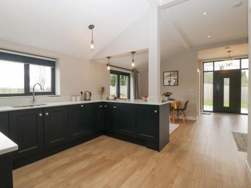 a kitchen with black cabinets and white counter tops at Medlands in Newent