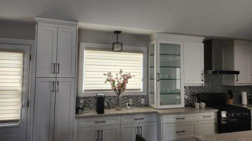 a kitchen with white cabinets and a vase of flowers at Amazing property to Enjoy. in Stouffville