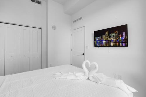 a white bedroom with a white bed with a bow on it at Miami Magic Vibrant 2 Bedroom with Free Parking in Miami