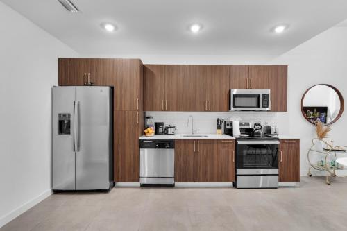 a kitchen with stainless steel appliances and wooden cabinets at Miami Magic Vibrant 2 Bedroom with Free Parking in Miami