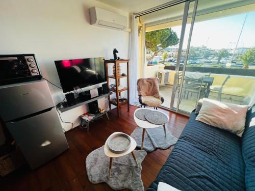 uma sala de estar com um sofá e uma televisão em Residence PORT NATURE by 8-HOMES vue Port em Cap d'Agde