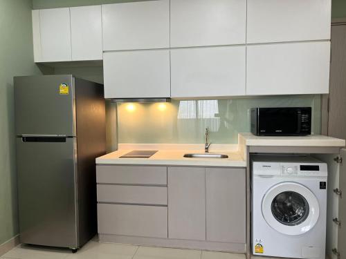 a kitchen with white cabinets and a washing machine at De-Luxe Residence in Phnom Penh