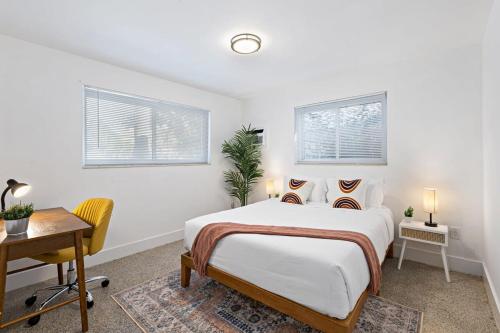 a bedroom with a bed and a desk and two windows at Lake Ridge Villa - Free Parking in Fort Lauderdale
