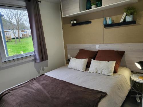 - un lit avec deux oreillers dans une chambre dotée d'une fenêtre dans l'établissement Vacances en Mobil home à Piriac sur mer, à Piriac-sur-Mer