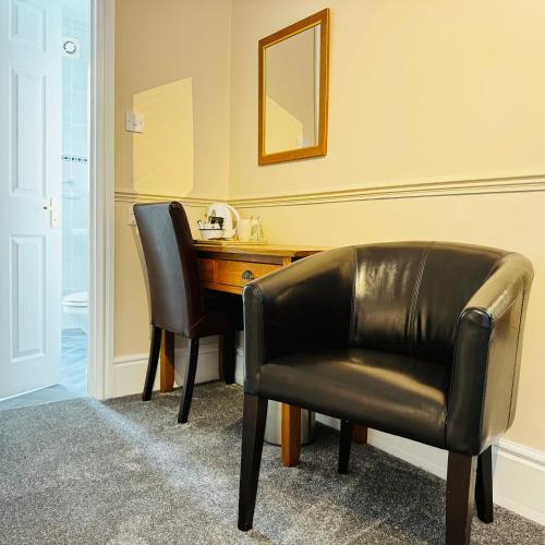 a desk and a leather chair in a room at Fairlawns Guest House in Banbury