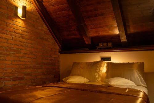 a bed with two pillows and a brick wall at Studio apartman & Wine House ONDINE in Zmajevac