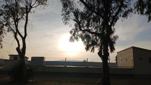 una puesta de sol sobre una cerca con un tren en la distancia en CAMPING DELTA NATURA LA TANCADA, en Amposta