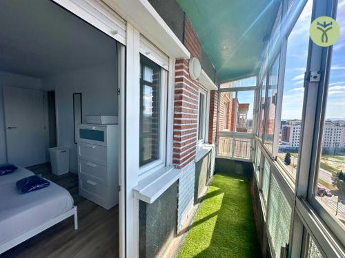 a room with a balcony with a bed and windows at Dos Torres Mozart - Atardecer en Zaragoza in Zaragoza