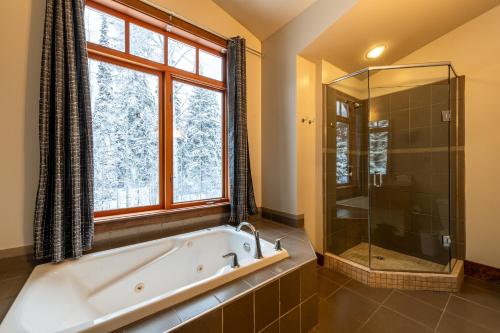 ein Bad mit einer Badewanne, einer Dusche und einem Fenster in der Unterkunft Copper Horse Lodge in Golden