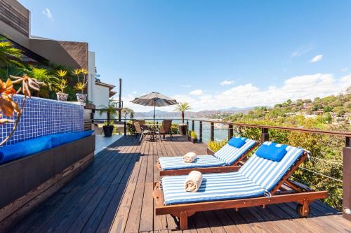 due sedie a sdraio su un ponte con vista sull'oceano di Hermosa Casa con Terraza y Vista al Lago en Avándaro a Valle de Bravo
