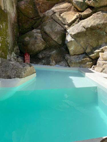 una piscina de agua azul con una casa en ella en Bloom Cottage I - Sintra montain, en Sintra