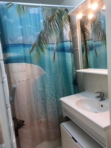 La salle de bains est pourvue d'un rideau de douche avec un palmier. dans l'établissement Jeux olympiques 2024, à Montigny-le-Bretonneux