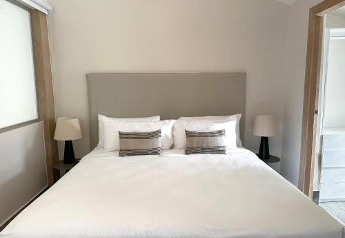a large white bed with two pillows and two lamps at AmazINN Places Casa del Mar in Panama City