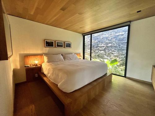 a bedroom with a large bed with a large window at Cabaña Roble Boutique en Avándaro, Valle de Bravo in Valle de Bravo