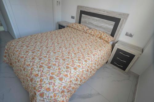 ein Schlafzimmer mit einem Bett mit einer orangefarbenen Bettdecke in der Unterkunft Cómodo apartamento en Playa Gandia in Los Mártires
