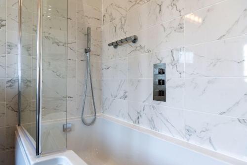 a white bathroom with a shower and a tub at Heathgate House Apartment in Budleigh Salterton