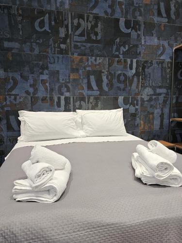a white bed with towels on it with a wall at Binario1 Rooms in Barletta