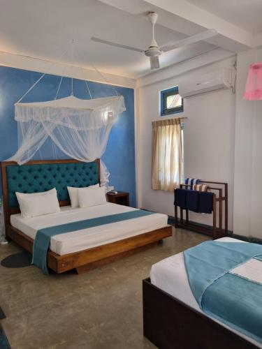 1 dormitorio con 2 camas y pared azul en Darshana Beach Hotel en Kosgoda