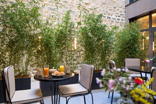 a patio with tables and chairs and plants at Maison Cassandre in Paris