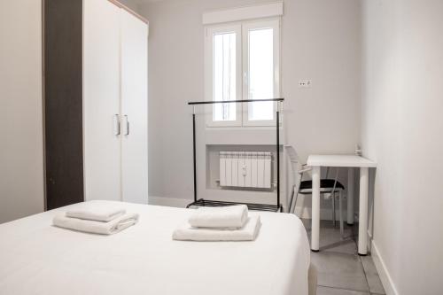 a white bedroom with a bed with two towels on it at Luz y Diseño en Retiro - Apartamento de 4 Dormitorios in Madrid