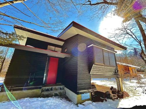 a house with a red door in the snow at HARUNA VILLA - Vacation STAY 27961v in Kita-karuizawa