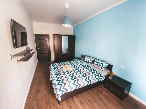 1 dormitorio con cama y pared azul en City Center Apartment en Chisináu
