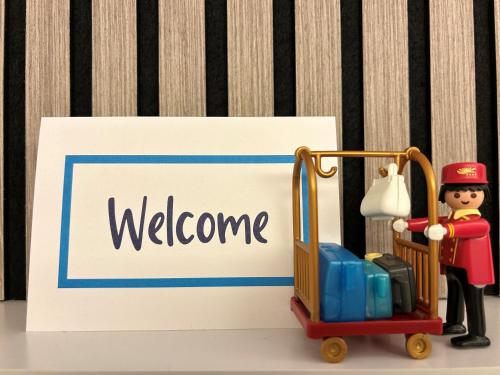 a lego man pushing a luggage cart next to a welcome sign at Villa Hotel Frankfurt by MZ HotelCollection in Frankfurt