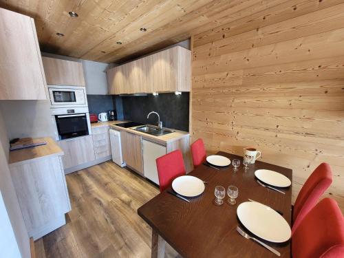 une cuisine avec une table en bois et des chaises rouges dans l'établissement Appartement rénové 3* au pied des pistes, balcon, parking, WiFi, pour 4 personnes - FR-1-598-133, aux Gets