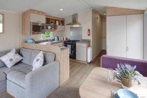 a living room with a couch and a kitchen at Campsie Glen Holiday Park in Glasgow