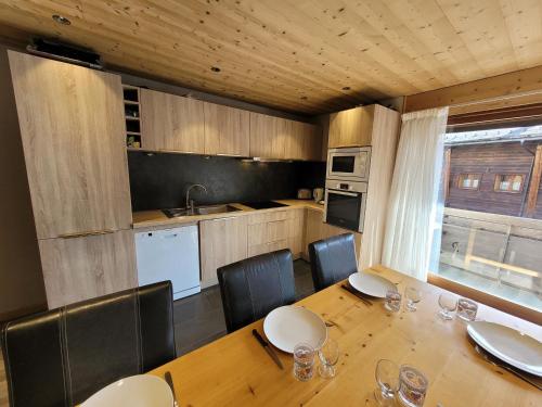 une cuisine avec une table en bois et des chaises ainsi qu'une salle à manger dans l'établissement Appartement rénové aux Gets avec balcon, 3 chambres, WiFi, parking - FR-1-598-122, aux Gets