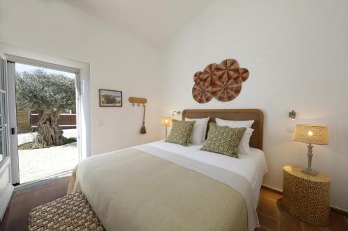 um quarto com uma cama grande e uma janela em Quinta Baltazar Casa particular em Vila Nova de Cacela