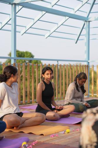 un grupo de tres mujeres sentadas en esterillas de yoga en House Of Surf Hostel for Women, en Varkala