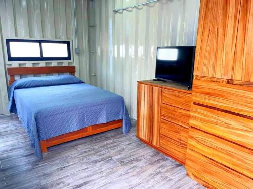 Schlafzimmer mit einem Bett und einem Flachbild-TV in der Unterkunft OHANA HOTEL & VILLA in Tierra Blanca