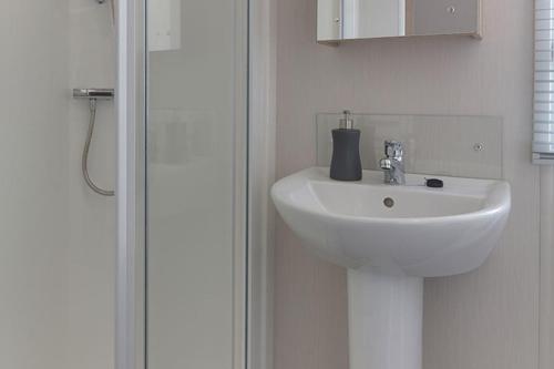 a white sink in a bathroom next to a shower at Campsie Glen Holiday Park in Glasgow
