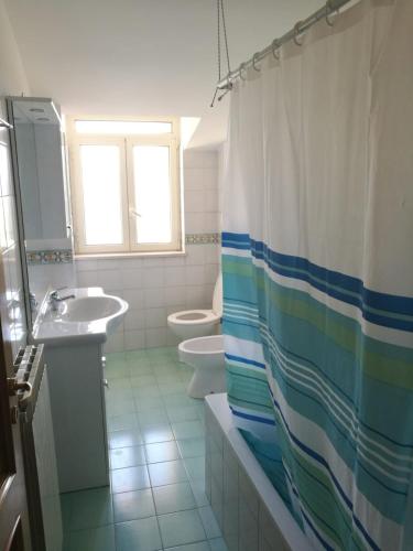 a bathroom with a sink and a toilet and a shower curtain at Grecale in Centola