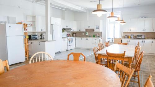 - une cuisine avec une table, des chaises et des appareils électroménagers blancs dans l'établissement Auberge de Jeunesse des Balcons, à Baie-Saint-Paul